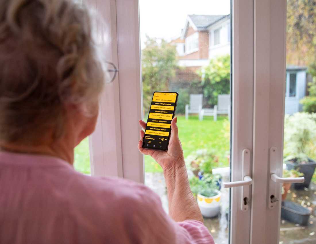 Woman looking at a magnified mobile phone screen showing talking newspaper options