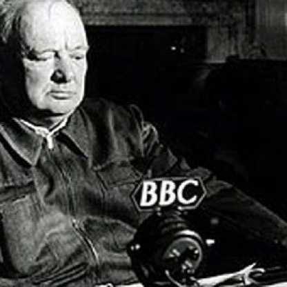 A grainy photo of Sir Winston Churchill sitting in front of a microphone with the letters BBC written on it.