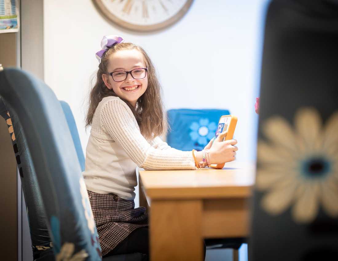 BWBF service user Annabel sits at a table holding her Voxblock audio book reader. A copy of Roald Dahl's Matilda is inserted.