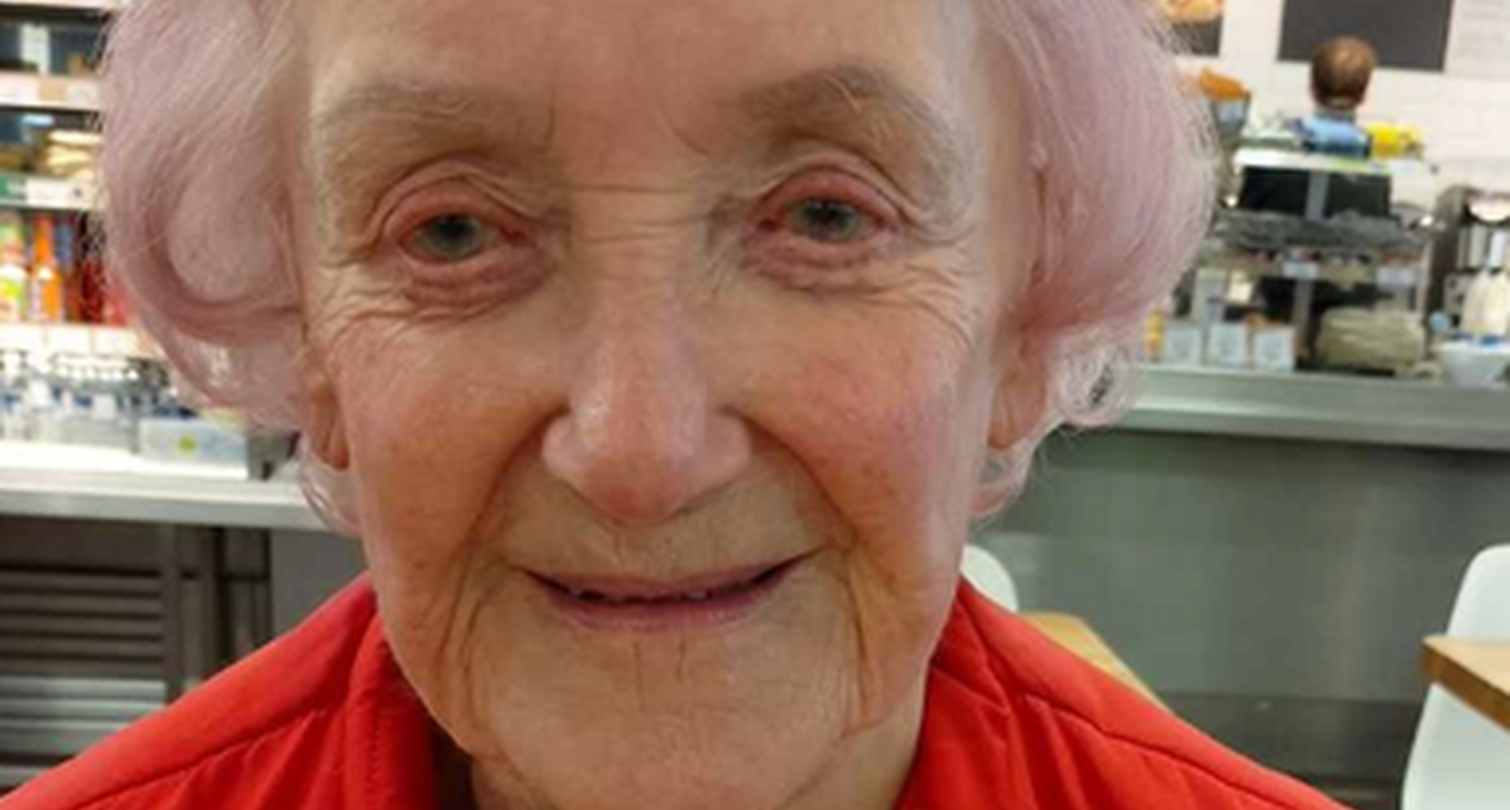 BWBF service user Jill Thomson smiling to camera. Wearing a red jacket and a badge that says I'm visually impaired.