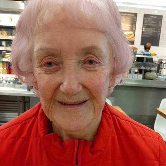 BWBF service user Jill Thomson smiling to camera. Wearing a red jacket and a badge that says I'm visually impaired.