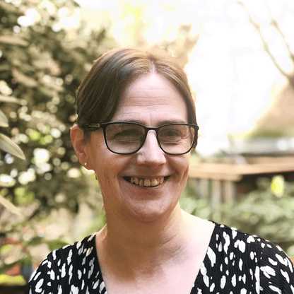 Alison Bates, Project Manager at BWBF, smiling and facing slightly to the side. She has brown hair tied back and is wearing glasses and a black top with a white pattern. Behind her is a garden in the background.
