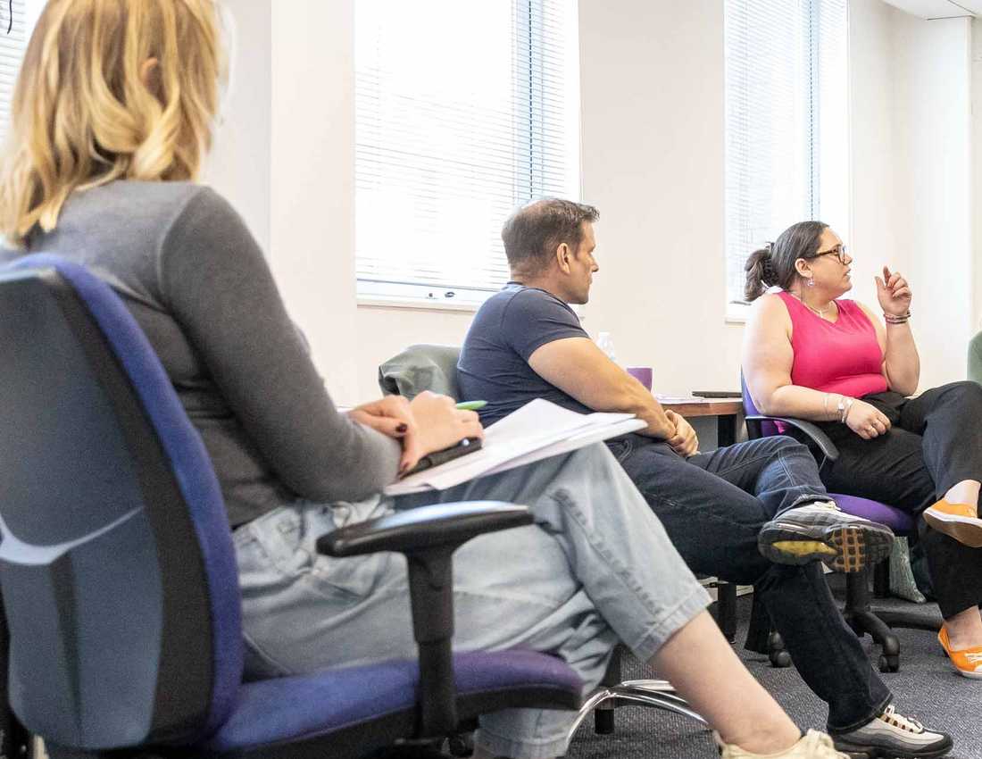 BWBF team members sit together in an office space discussing ideas at a team meeting