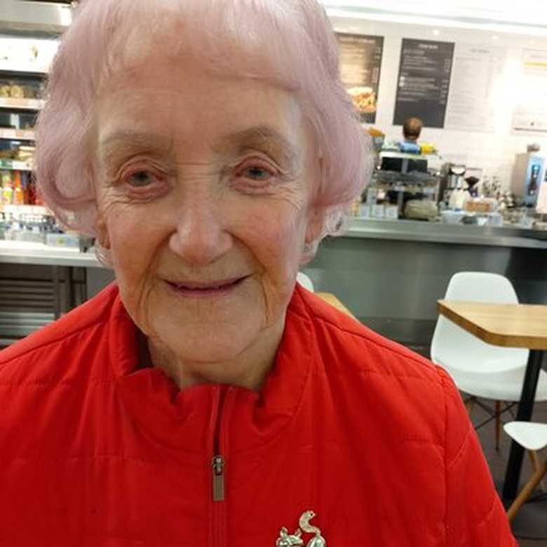 BWBF service user Jill Thomson smiling to camera. Wearing a red jacket and a badge that says I'm visually impaired.