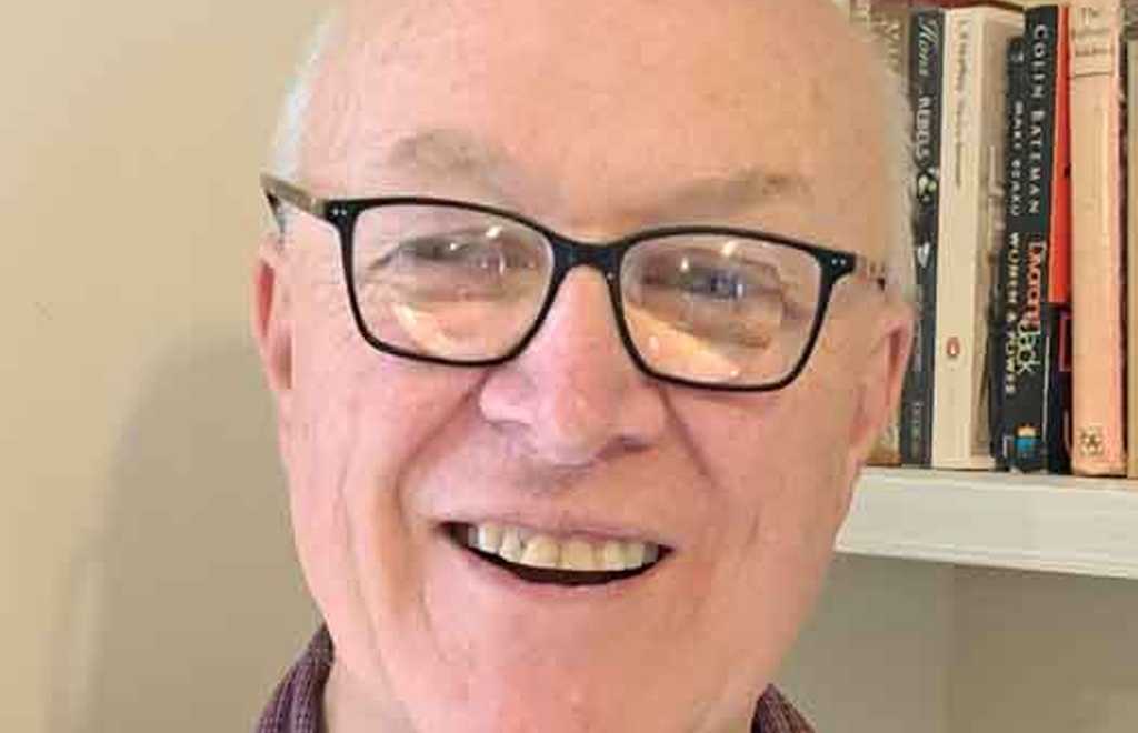BWBF Trustee John Beesley stands in front of a bookshelf. He is smiling broadly.