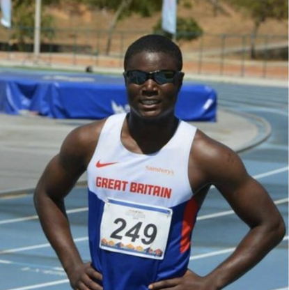 BWBF Patron Souleyman Bah is standing on an athletics track. He is wearing an athlete's vest and sunglasses.