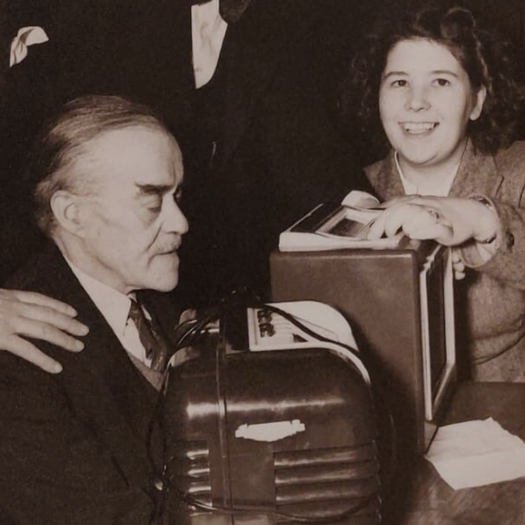 A black and white photo of people gathered around a Bush DAC10 radio, given to BWBF in the 1950s