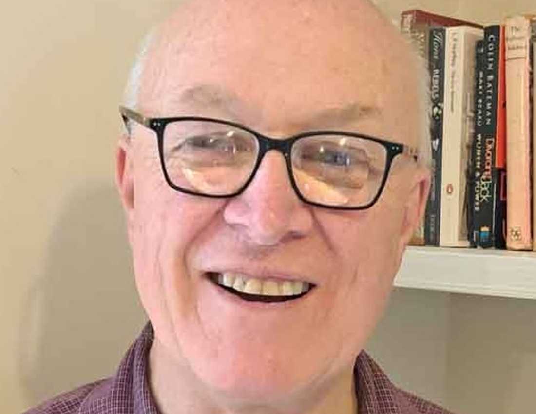BWBF Trustee John Beesley stands in front of a bookshelf. He is smiling broadly.