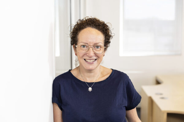 A photo of BWBF's Individual Giving and Legacy Manager Julie Hocking. She is wearing a dark t-shirt and glasses and her curly hair is tied up.